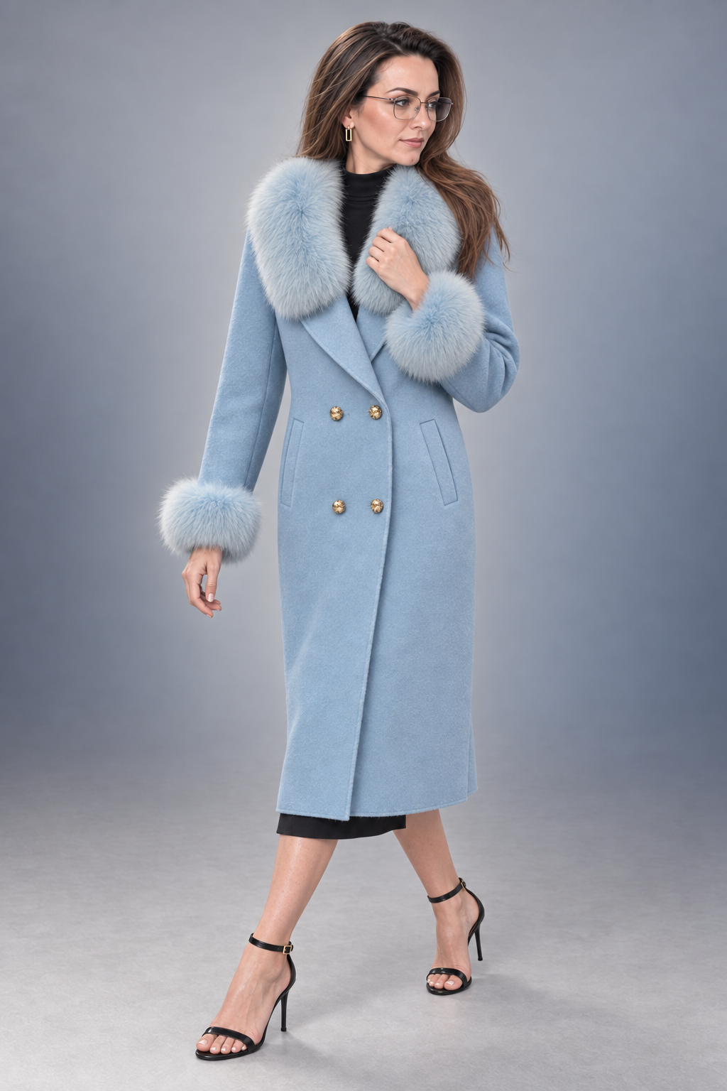 A woman models a light blue double-breasted coat with a fluffy light blue fur collar and cuffs, paired with black high-heeled sandals against a gray studio background.