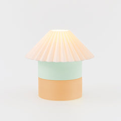 Table lamp with a pastel-colored base and pleated shade on a light gray background