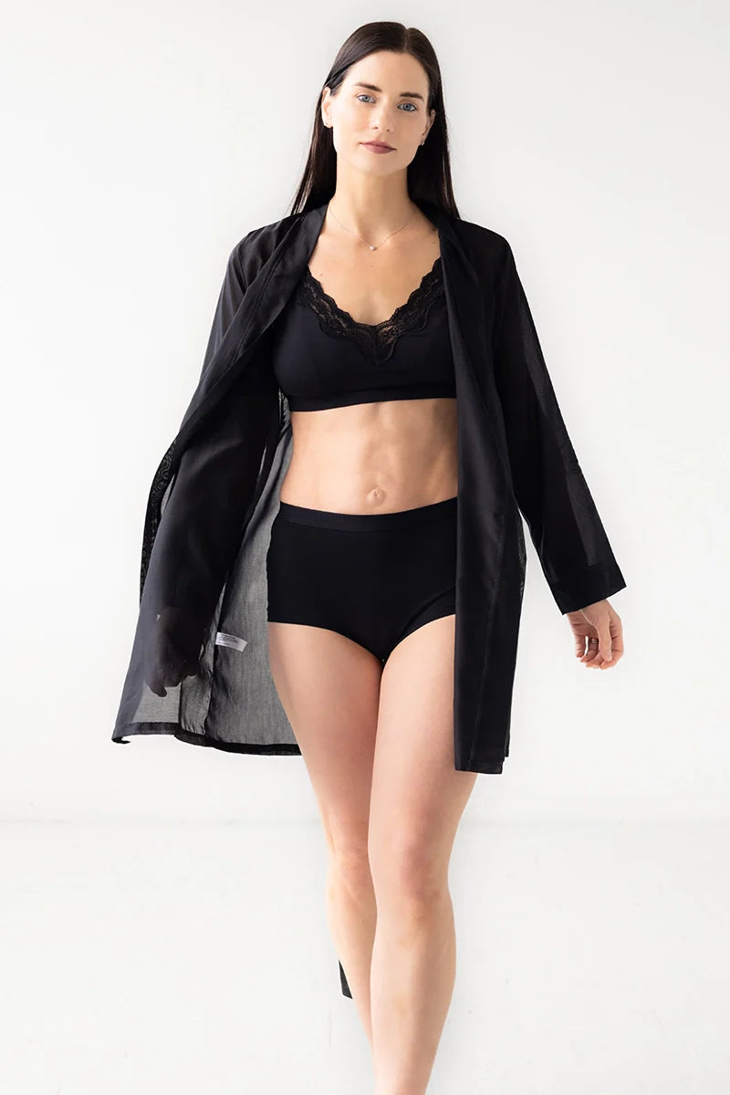 Woman wearing black lingerie and a black robe on a white background