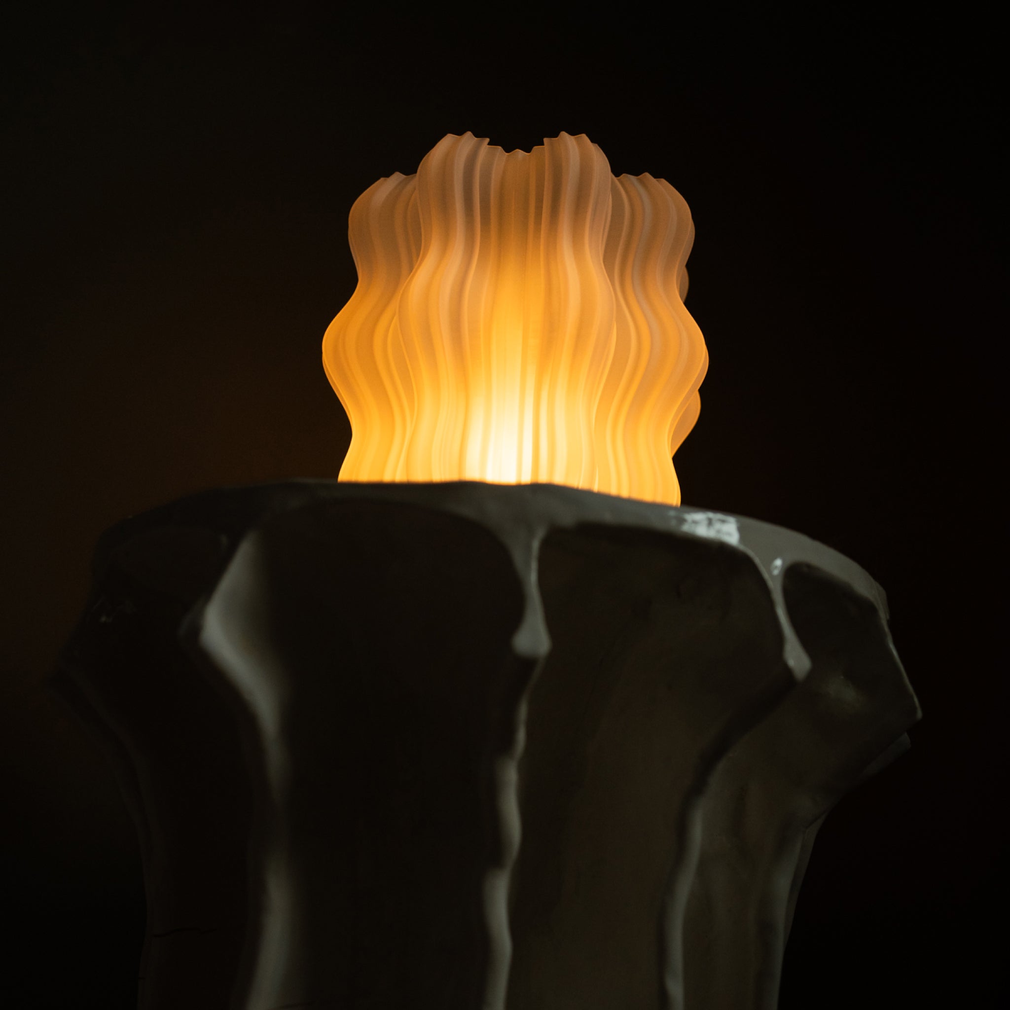 Decorative lamp with wavy design and warm glow on a dark background
