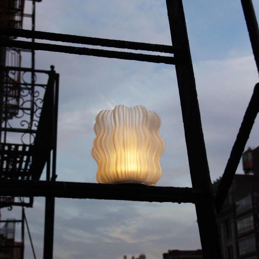 Decorative lamp with wavy design against a city skyline