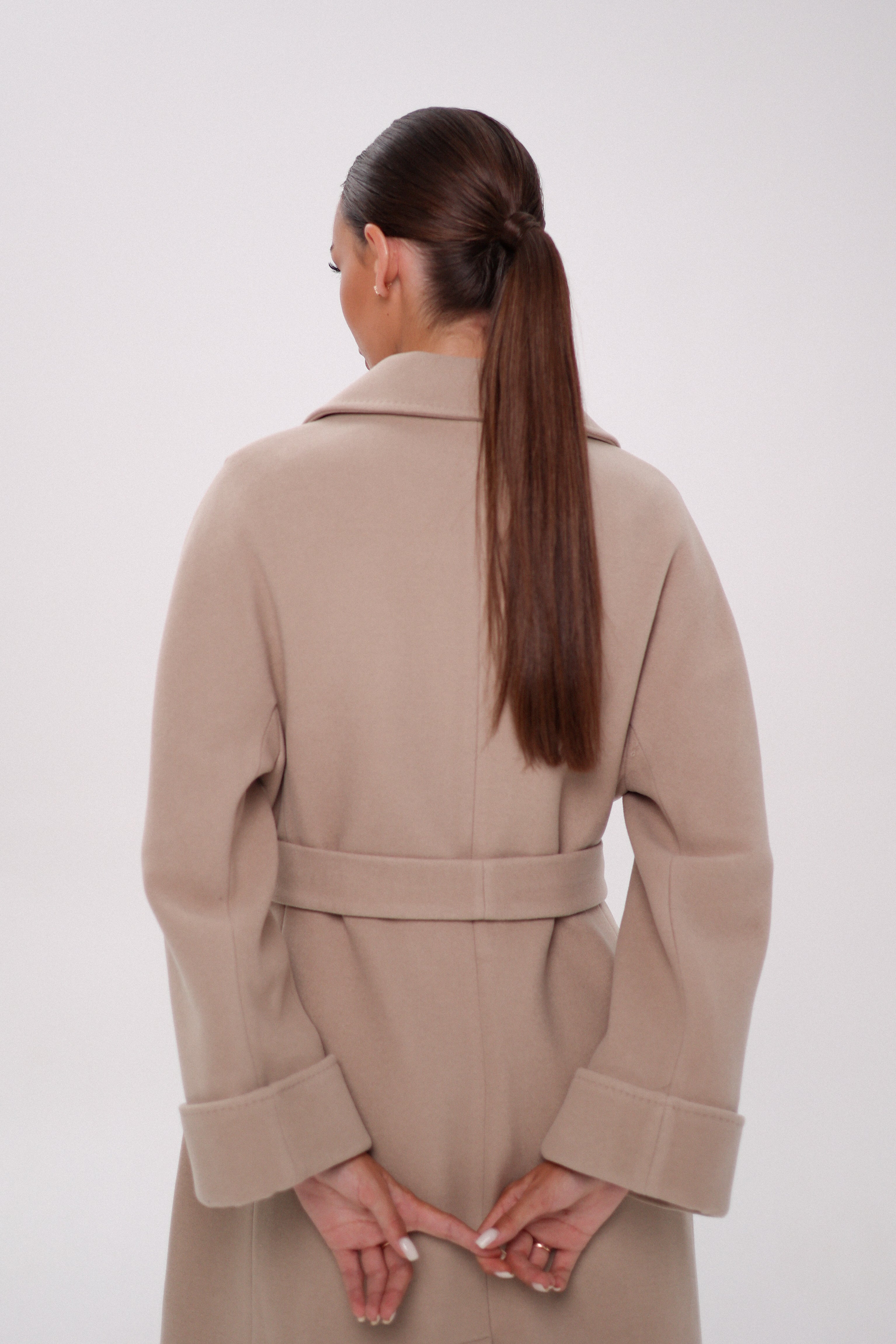 Woman wearing a beige coat on a white background