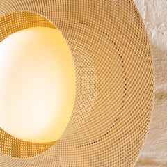 Round woven placemat with a glowing light bulb inside on a textured beige background