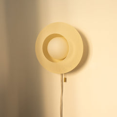 Gold wall-mounted lamp with textured design on a beige wall