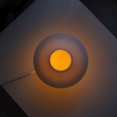 Round light fixture with a glowing yellow center on a dark background