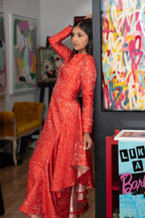 Woman in a red dress standing in an art gallery with colorful paintings on the walls.