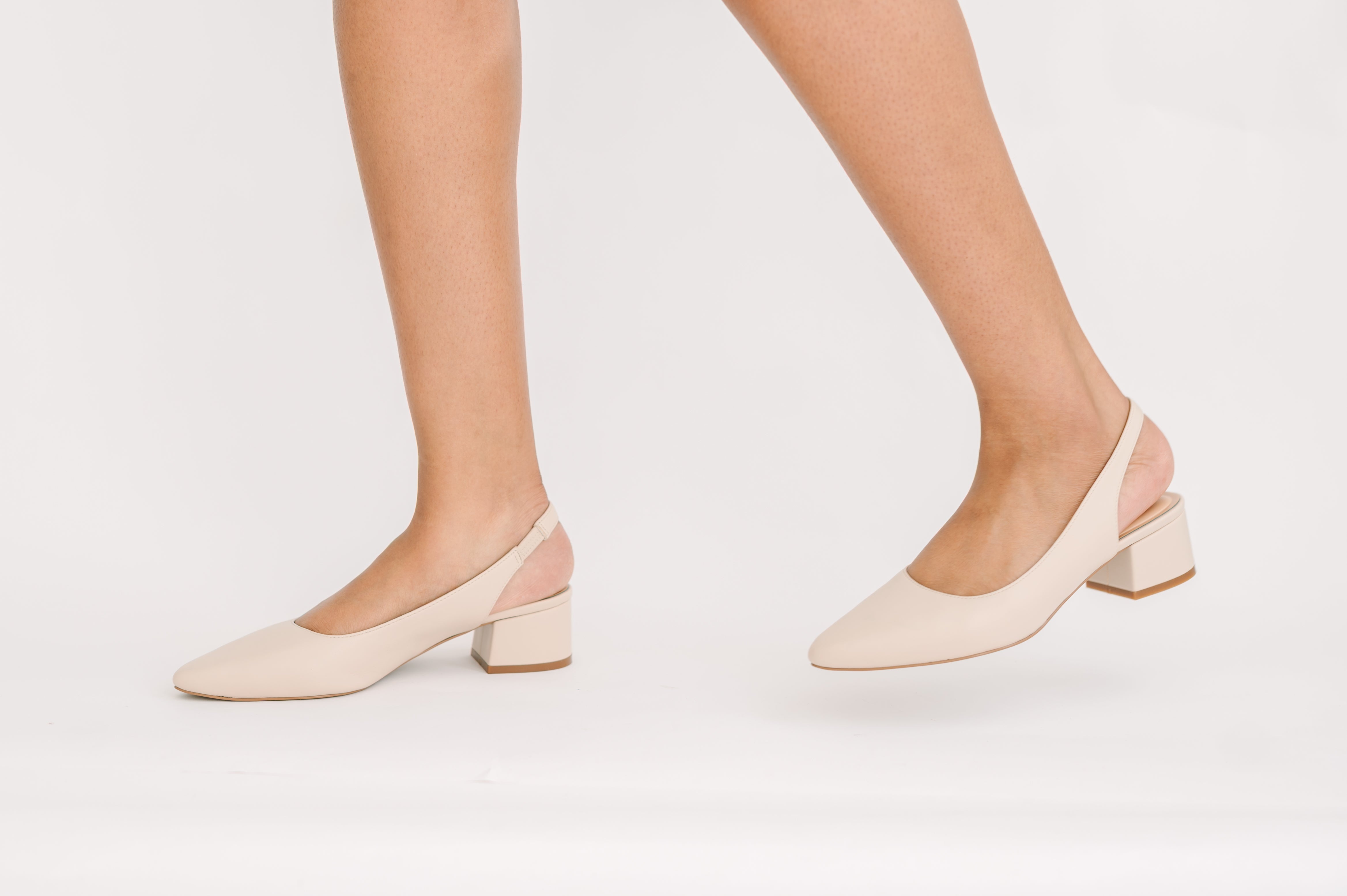 Beige high-heeled shoes worn by a person on a white background
