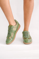 Green sneakers worn by a person on a white background