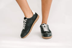 Black sneakers with white laces on a light gray background