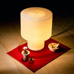 Decorative lamp on a red mat with small items on a wooden floor