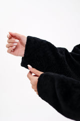 Close-up of a person wearing a black sweater with a white background