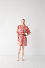 Woman wearing a pink robe against a white background
