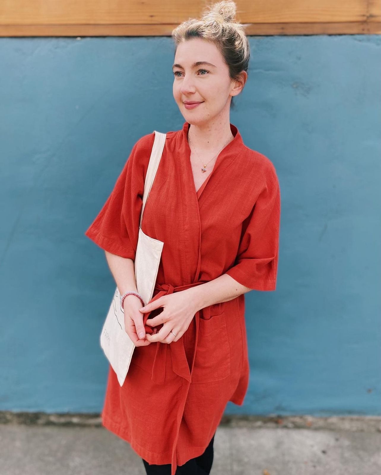 Woman wearing a red dress standing against a blue wall