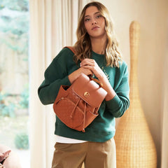 Woman holding a brown leather backpack indoors