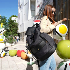 Woman with a black backpack walking on a street with colorful sculptures.