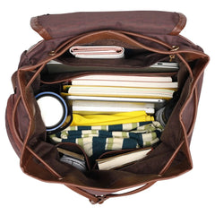 Brown leather bag with compartments filled with various items on a white background