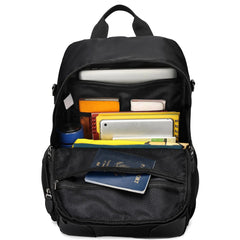 Black backpack with various items including books and a passport on a white background