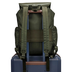 Green backpack on top of a blue suitcase with a white background