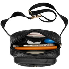Black handbag with a strap, containing a phone, wallet, and other items on a white background