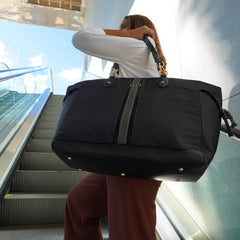 Person holding a large black duffel bag on an escalator
