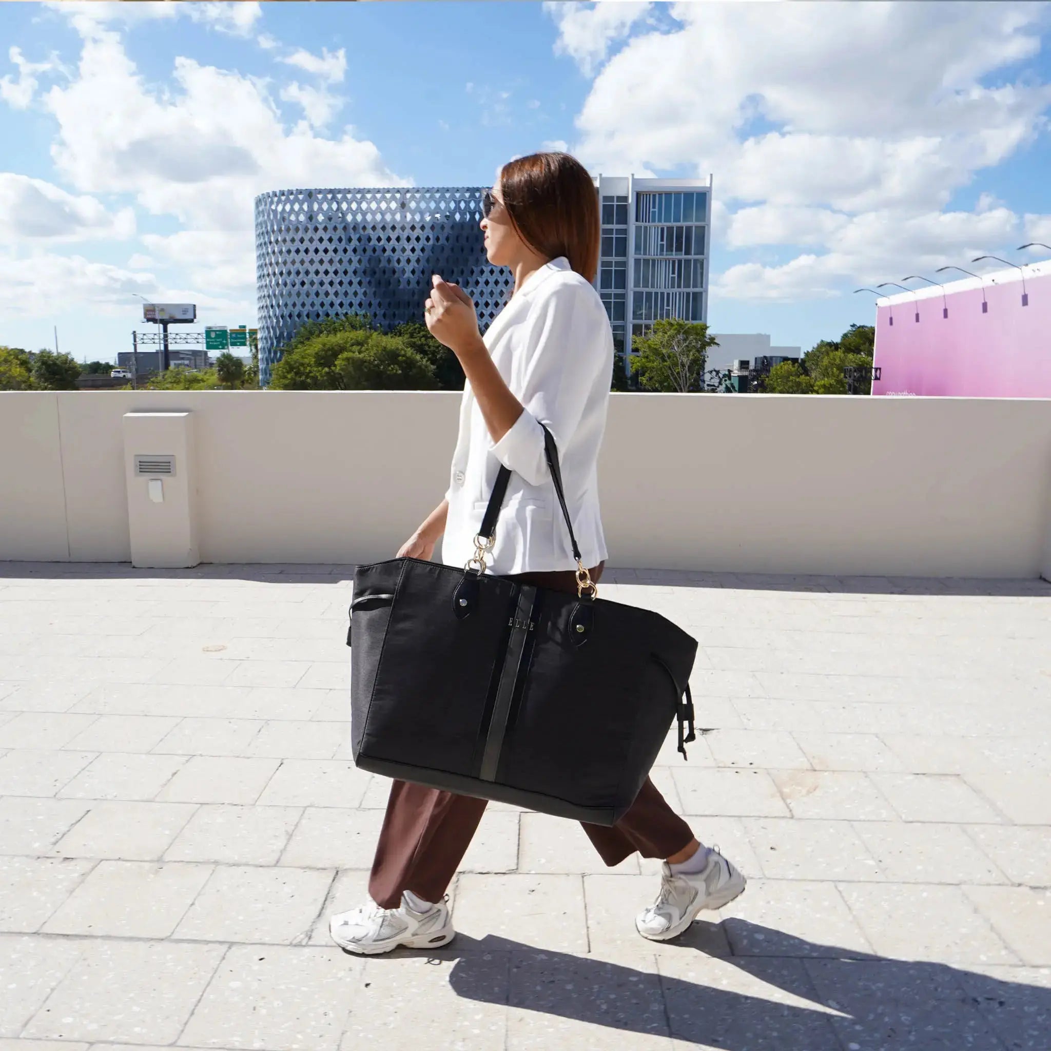 Person holding a black bag on a rooftop with buildings in the background