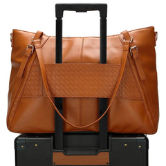 Brown leather bag with a black handle on a black suitcase