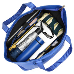 Blue tote bag with various items including a water bottle, sunglasses, and rolled-up towel.