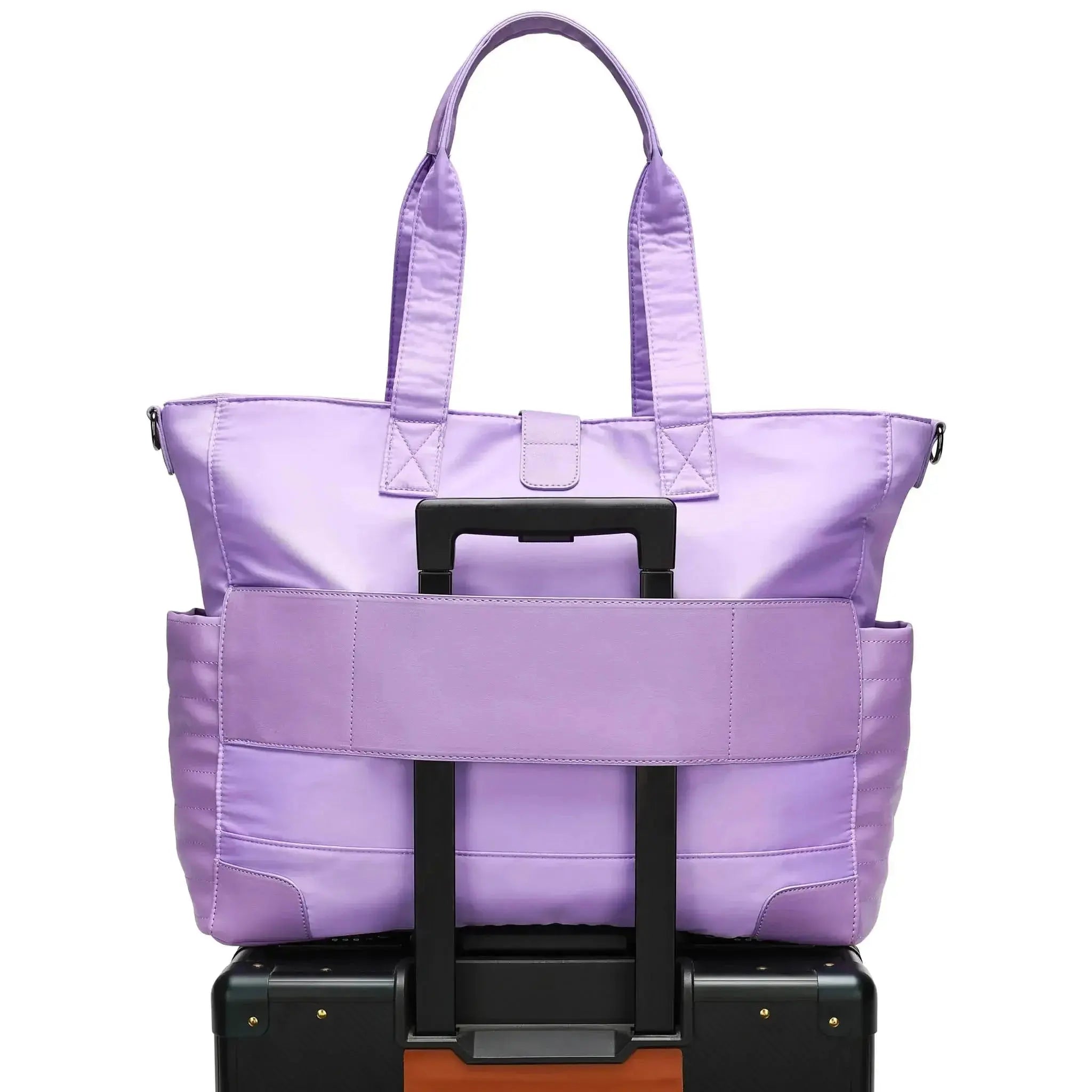 Purple tote bag on top of a black suitcase with a white background