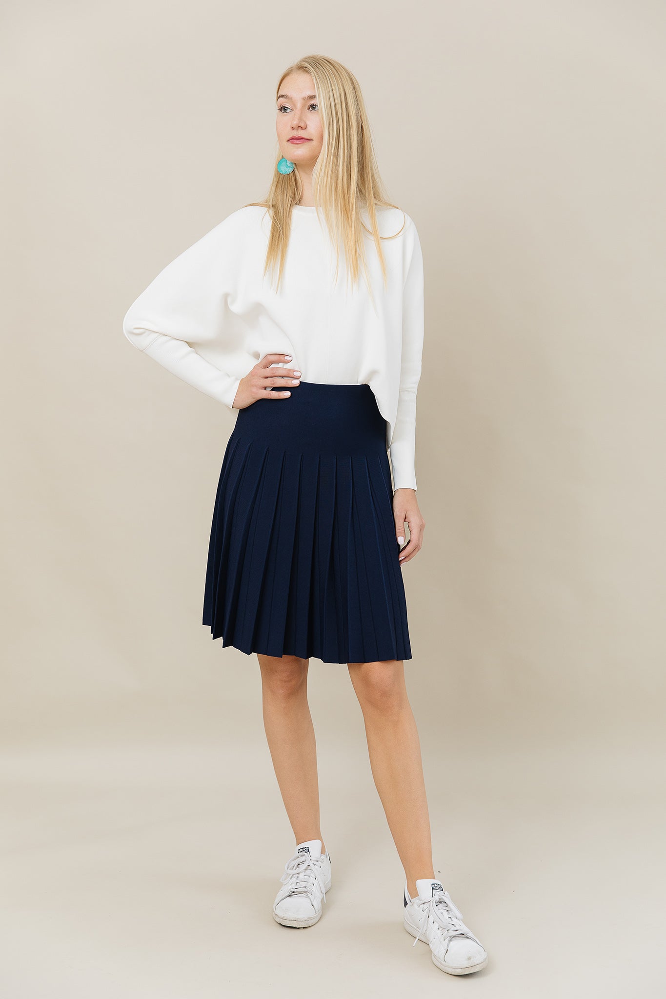 Woman wearing a white blouse and navy skirt on a beige background