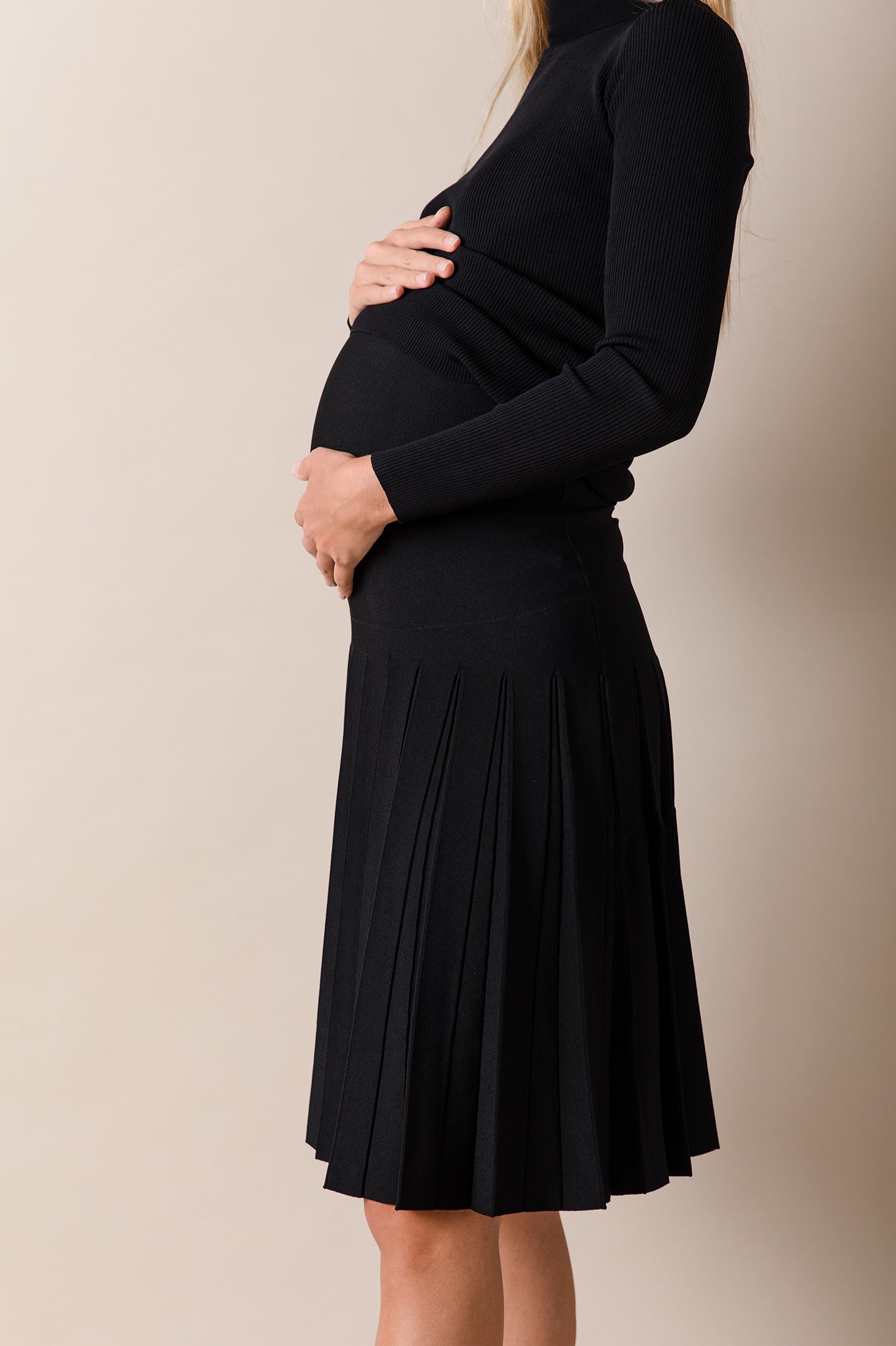 Person wearing a black dress against a beige background