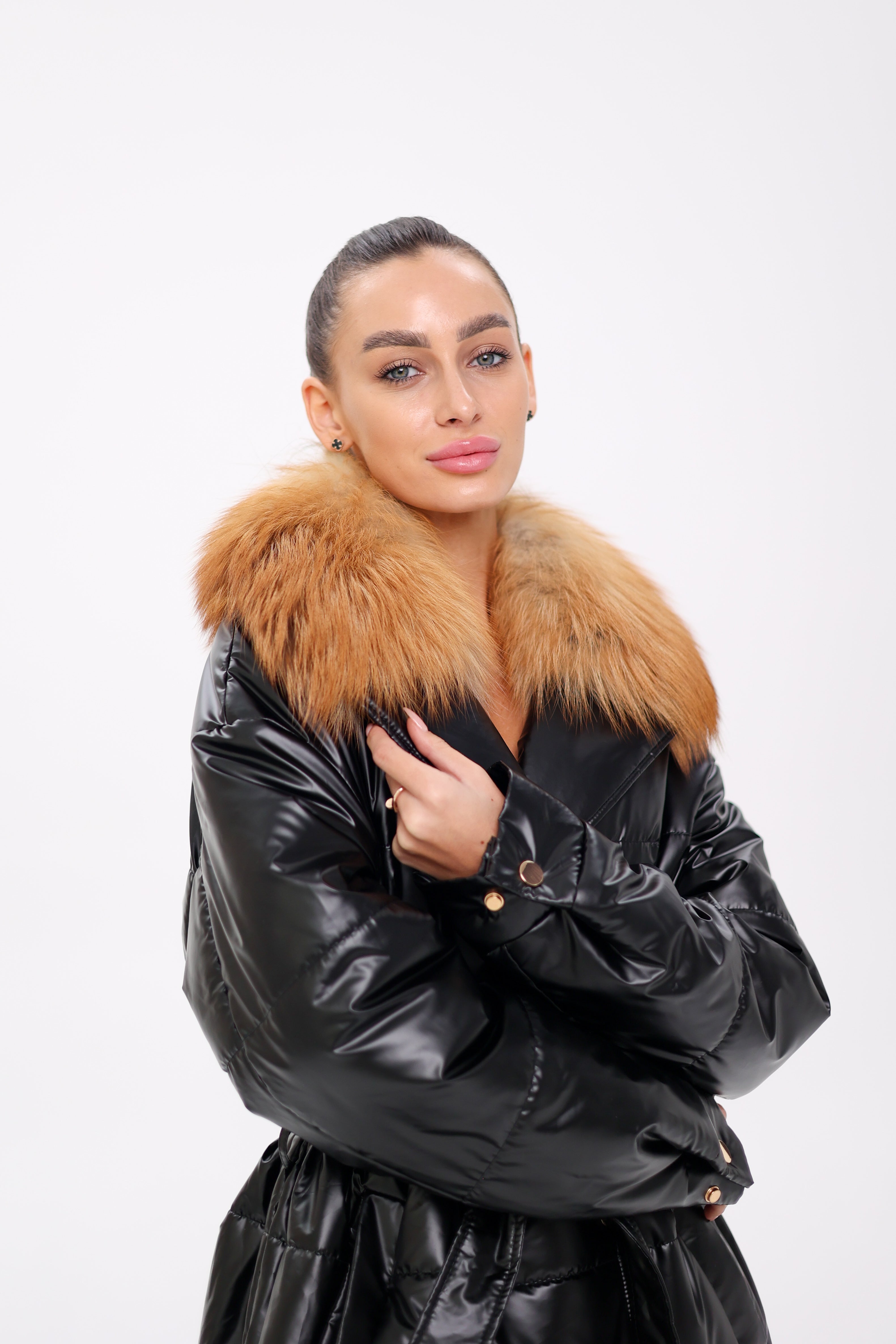 Woman wearing a black leather jacket with a fur collar on a white background