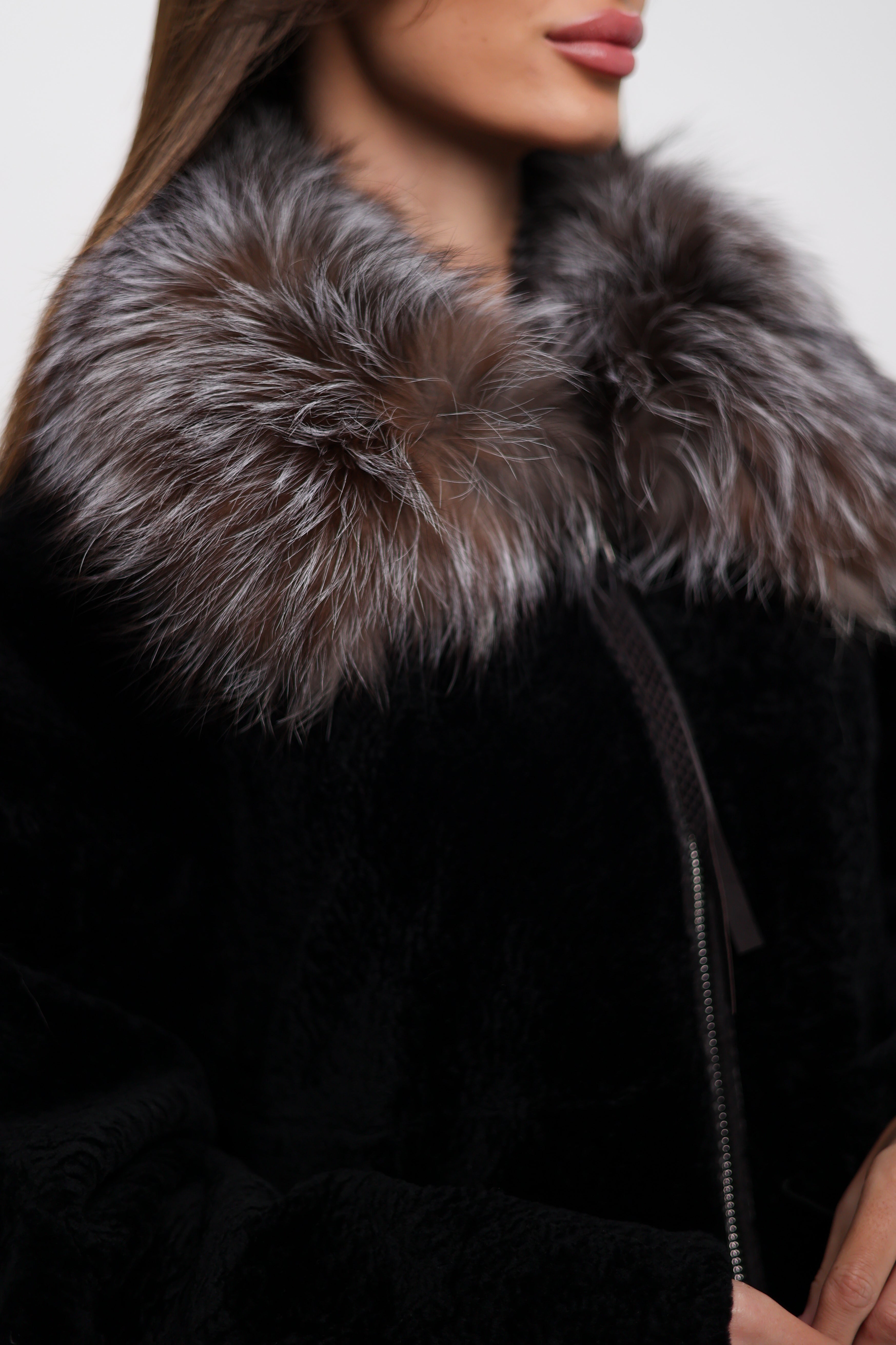 Close-up of a black coat with a fur collar on a neutral background
