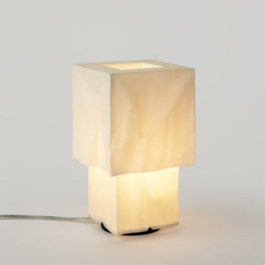 Square table lamp with a beige fabric shade on a light gray background