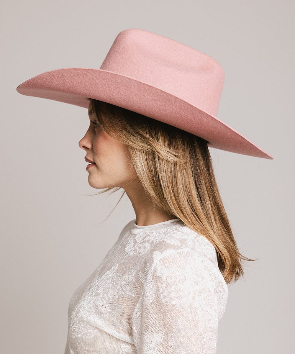 Person wearing a pink wide-brimmed hat against a plain background