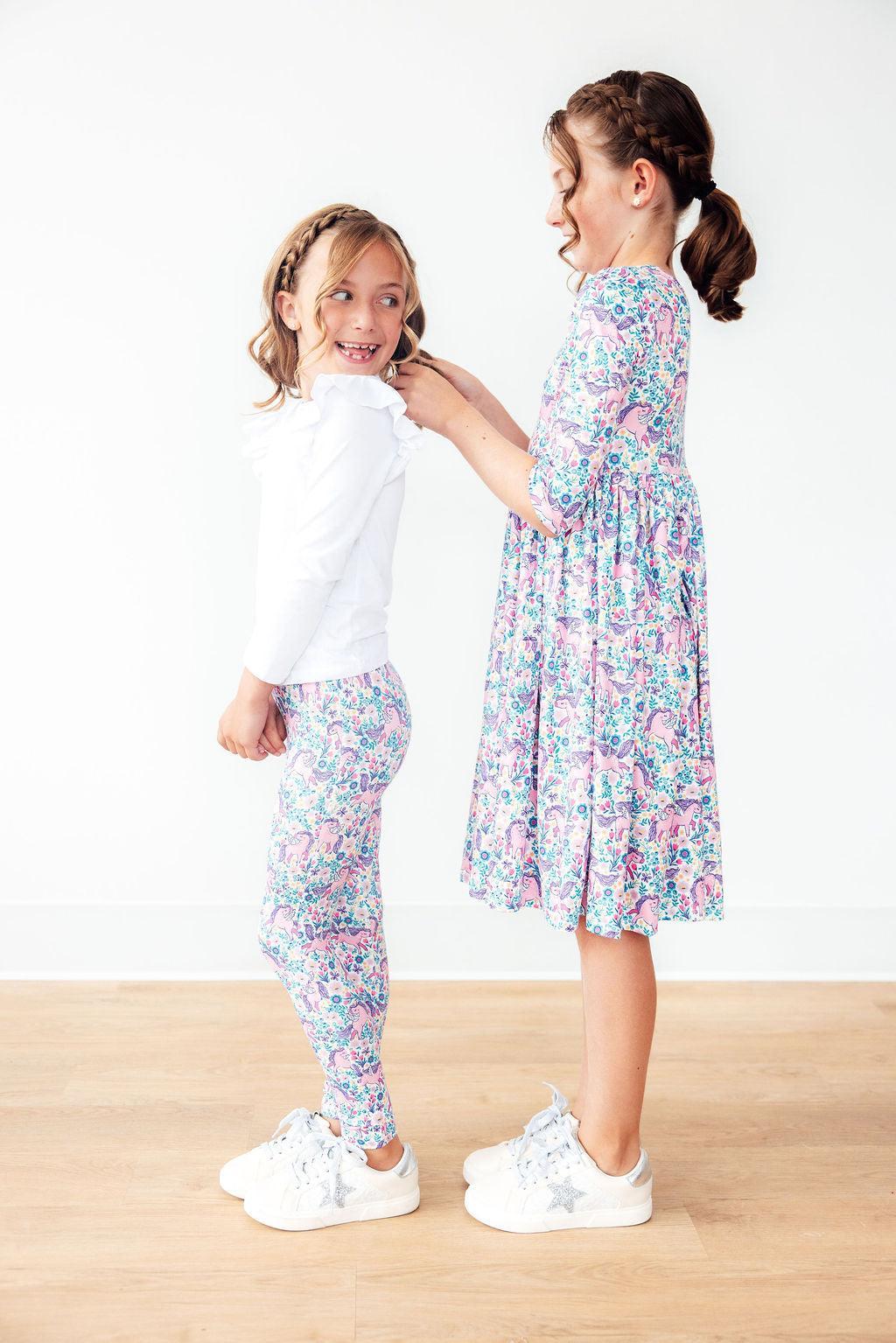 Two young girls wearing matching floral outfits on a white background