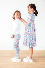 Two young girls wearing matching floral outfits on a white background