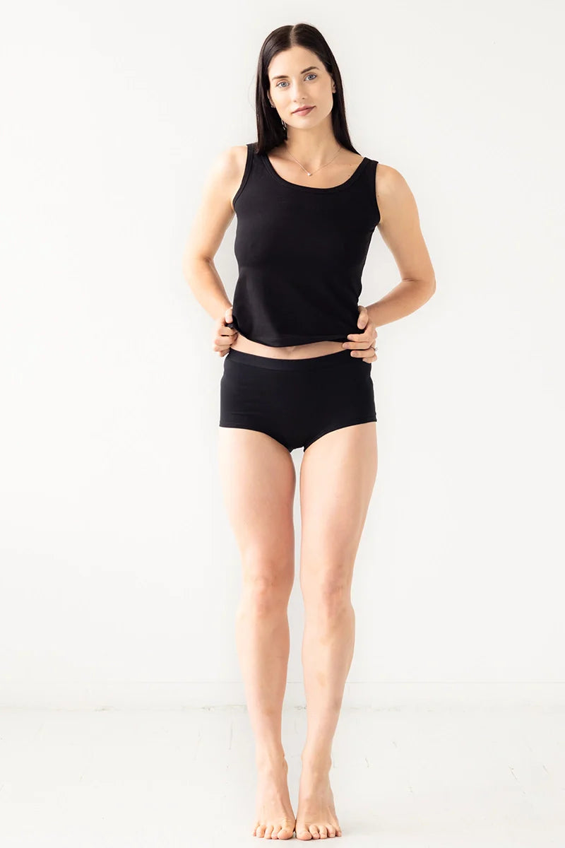Woman wearing a black tank top and black shorts on a white background