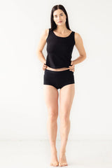 Woman wearing a black tank top and black shorts on a white background
