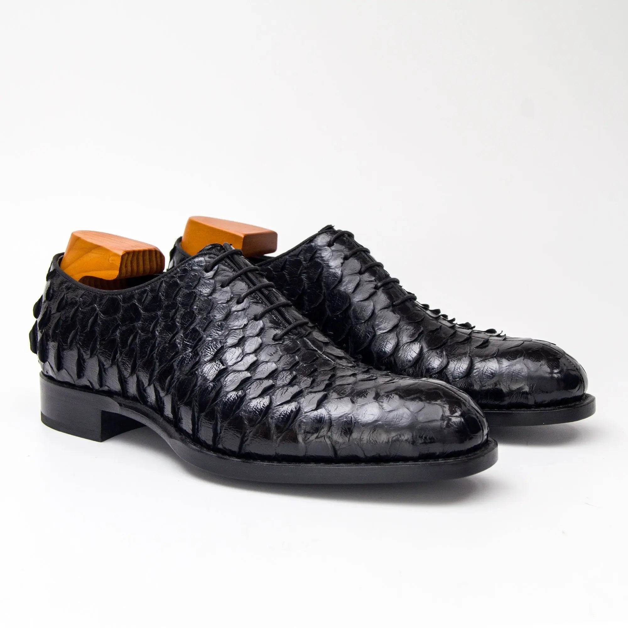 Black textured dress shoes with orange shoehorns on a white background