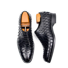 Black textured dress shoes with wooden soles on a white background