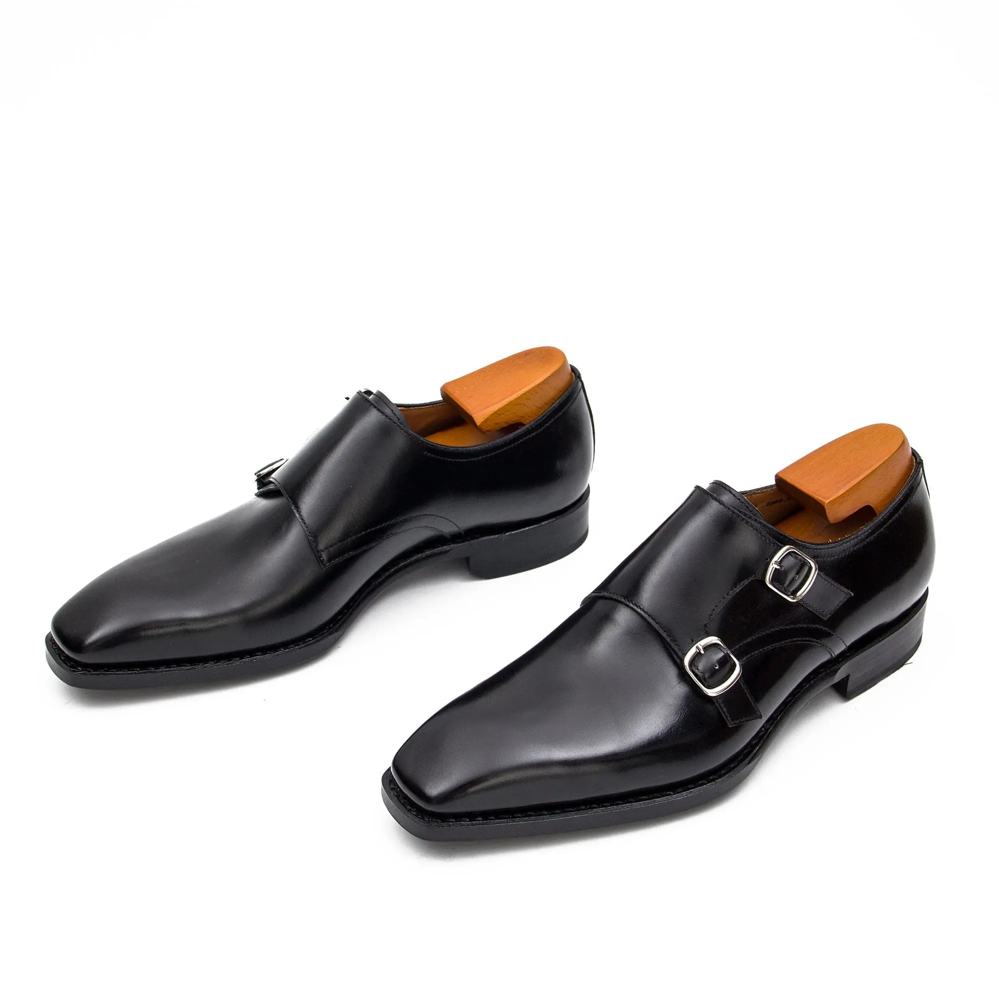 Pair of black dress shoes with brown soles on a white background