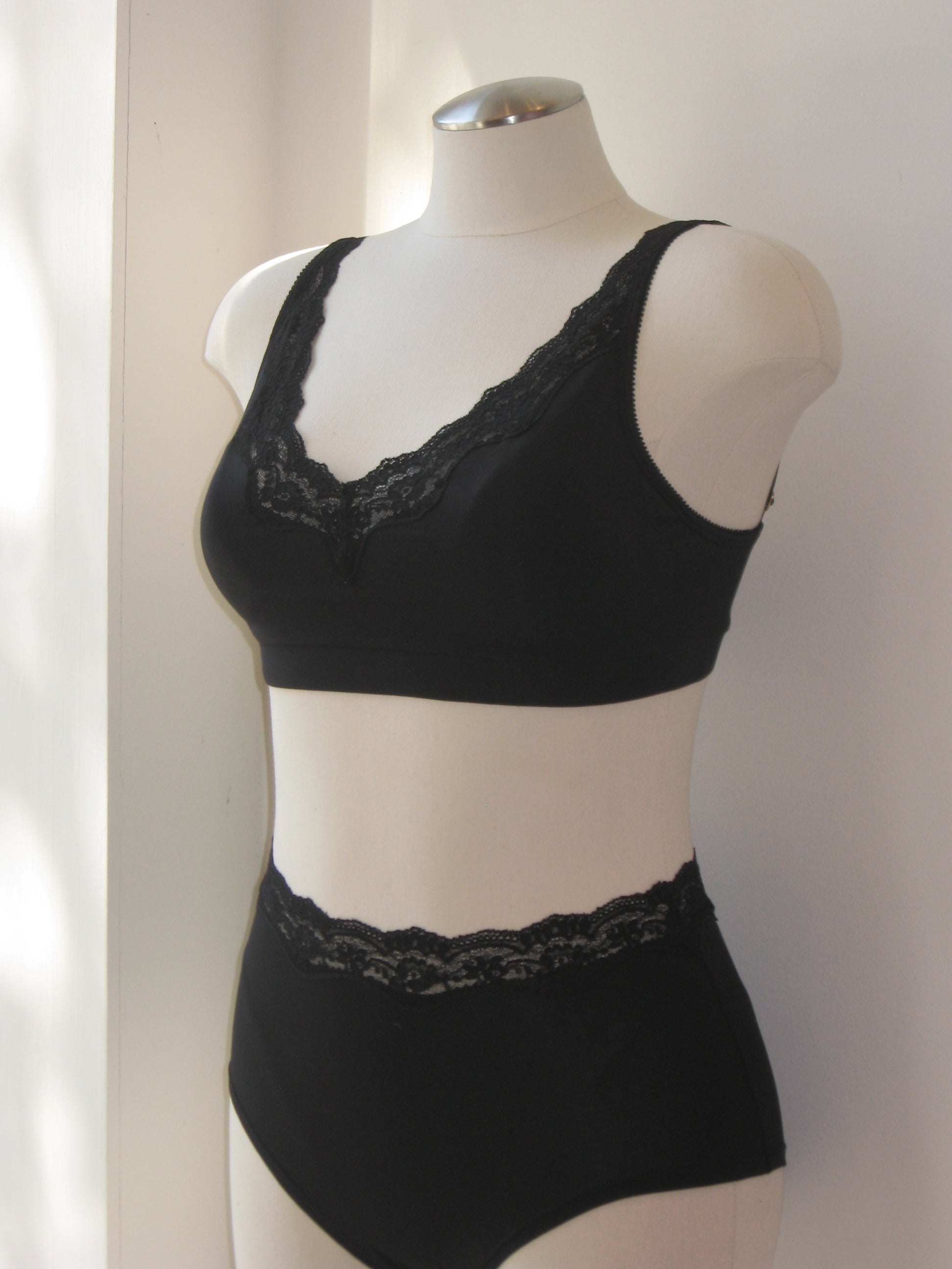 Black lace lingerie set on a mannequin against a neutral background