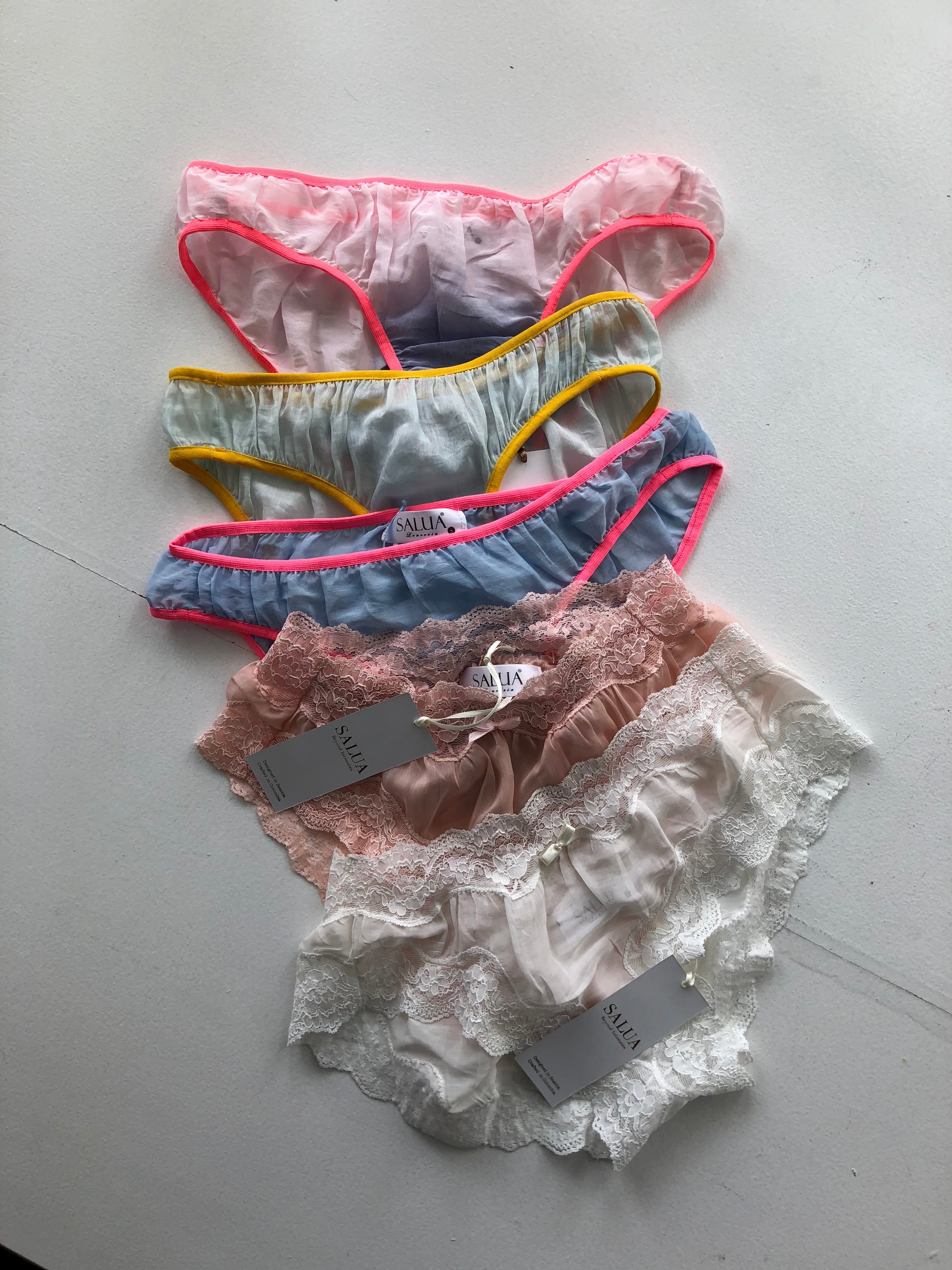Four pairs of women's underwear with tags on a gray surface