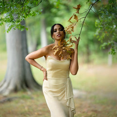 Woman in a light dress holding leaves in a forest setting