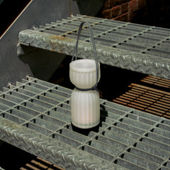 White lantern with a black cord on a metal grate