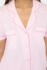 Pink pajama top with white buttons and pink piping on a white background