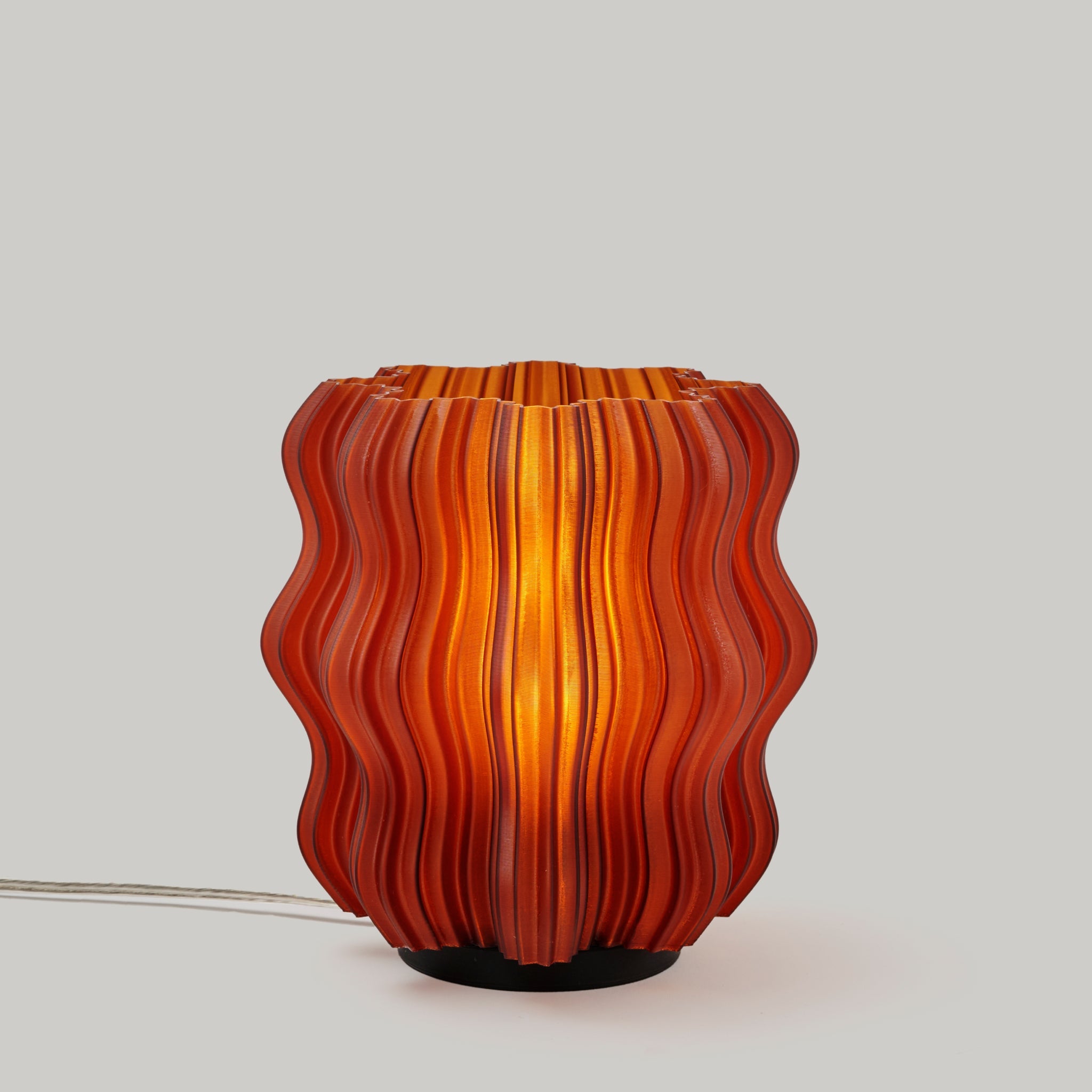 Decorative lamp with wavy orange and red design on a light gray background