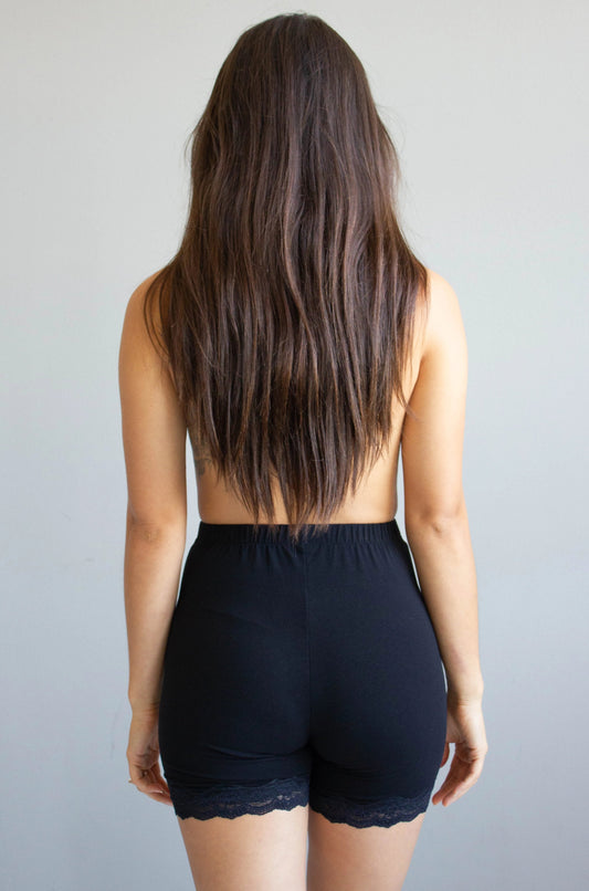 Person wearing black shorts from behind on a plain background