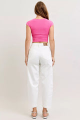 Person wearing a pink top and white pants on a plain background