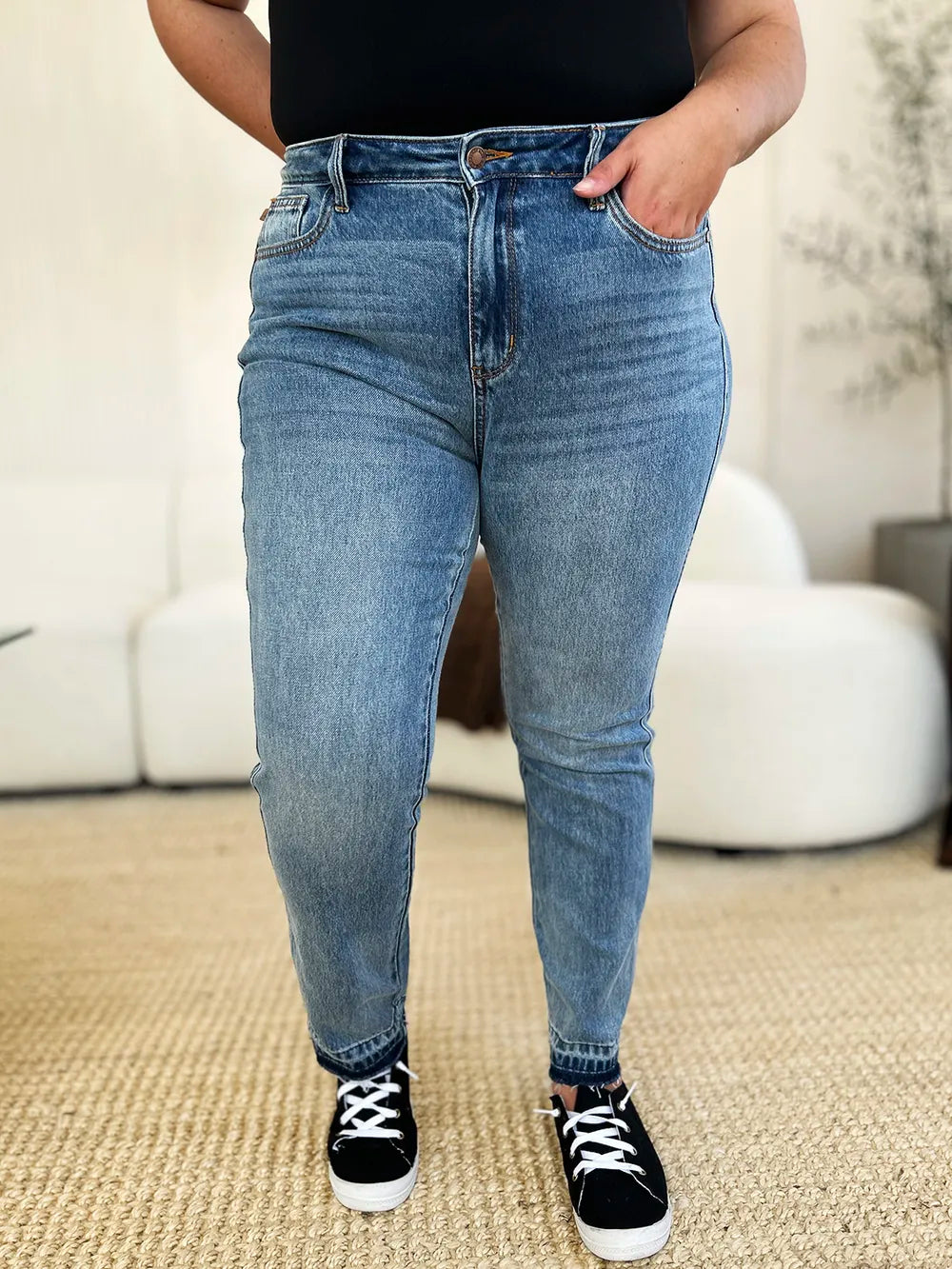 Person wearing blue jeans and black sneakers in a casual setting
